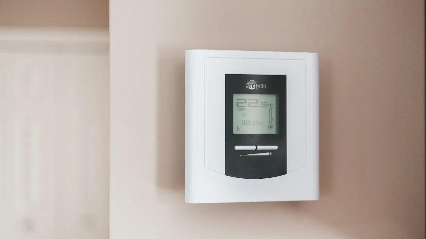 Main réglant un thermostat de chauffage mural